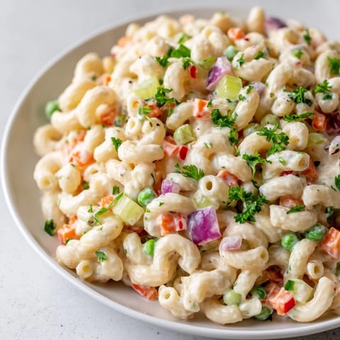 Creamy macaroni salad, chilled and ready, with diced vegetables and tender pasta visible.