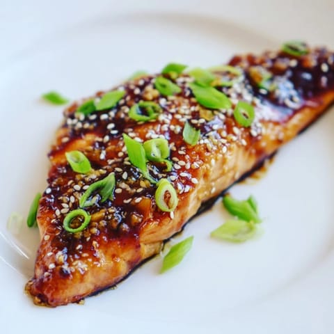 Close-up of flaky Honey Garlic Salmon with a savory sauce, garnished for flavor.