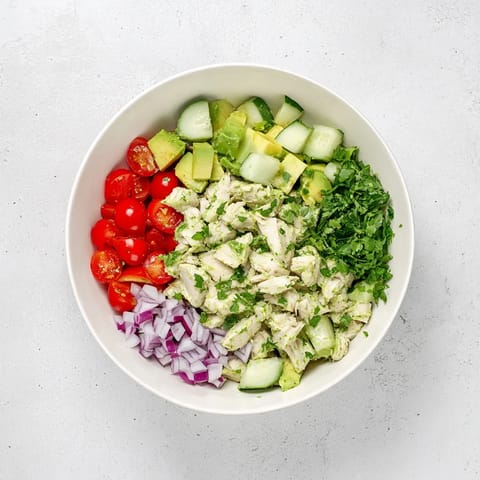 A vibrant bowl of Avocado Chicken Salad featuring shredded chicken, crisp cucumber, red onion, and fragrant cilantro.