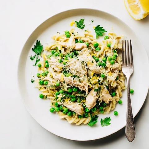 A close-up of Garlic Butter Chicken & Pea Pasta showing golden chicken and vibrant peas nestled in creamy, glossy fusilli.  