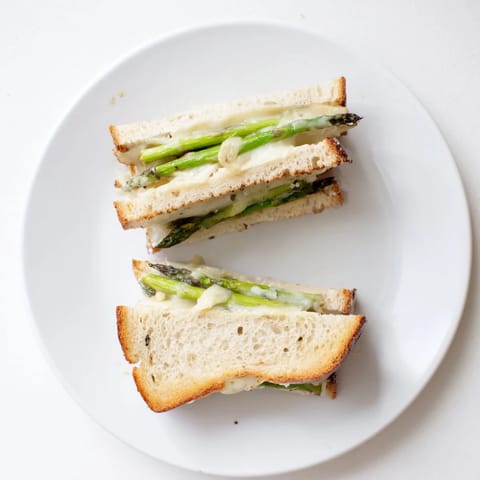 Asparagus and Brie grilled cheese, with creamy melted cheese oozing from between buttery toasted bread slices.