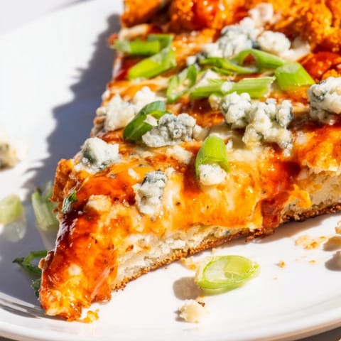 Freshly baked Buffalo Cauliflower Pizza with melted mozzarella, chopped green onions, and celery on a rustic wooden table.