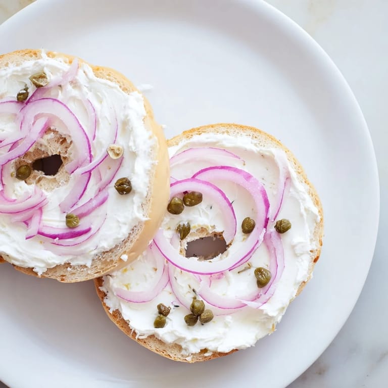 Golden toasted bagel with cream cheese, garnished with fresh dill and tomato slices for a flavorful bite.