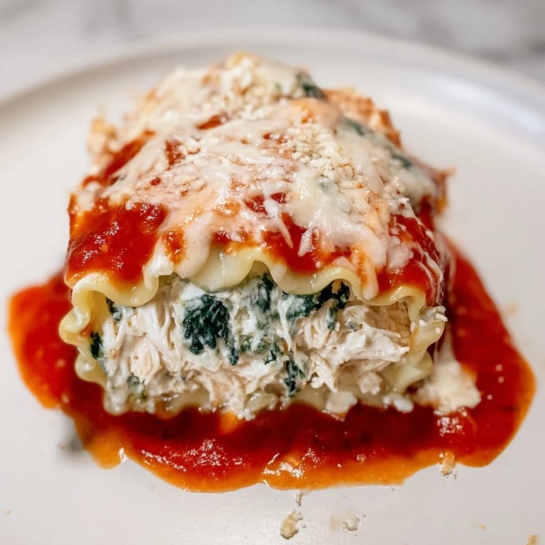 A close-up of Chicken and Spinach Lasagna Rolls reveals layers of creamy ricotta and vibrant green spinach.
