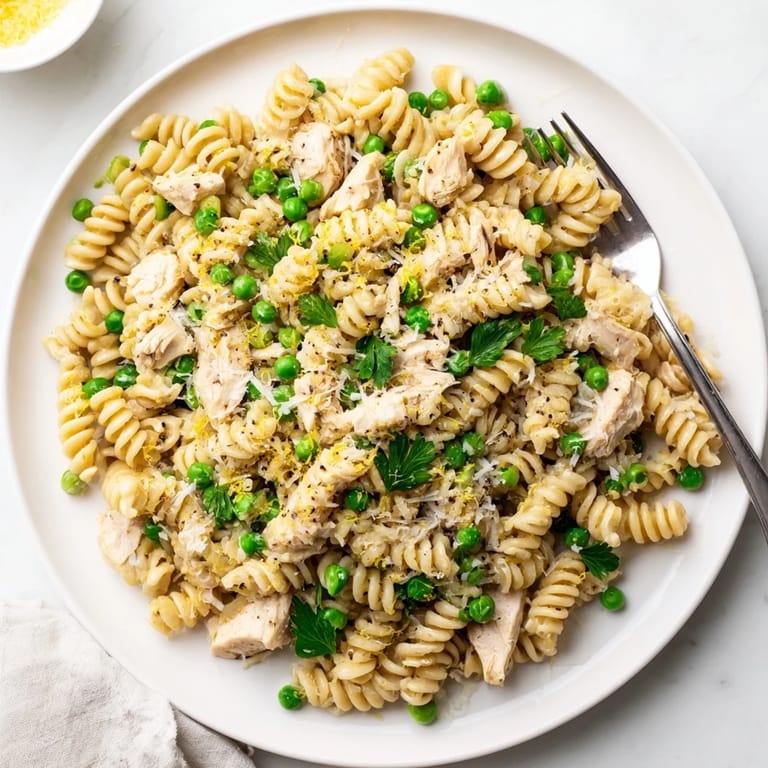 Garlic Butter Chicken & Pea Pasta in a skillet, fresh parsley and lemon zest garnish for a family-friendly Italian-inspired meal.  