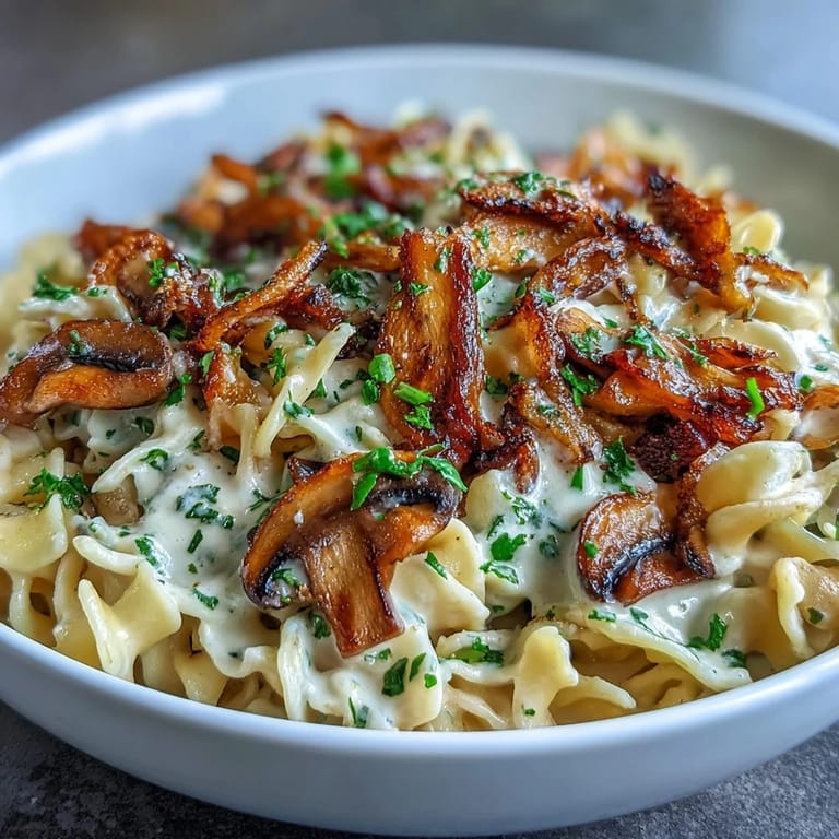 Vegetarian stroganoff with golden onions and browned mushrooms, served steaming hot over egg noodles.