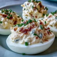 Twelve halved egg whites filled with creamy Million Dollar Deviled Eggs, dusted with paprika and fresh chives.