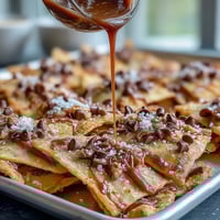 Candy Apple Nachos with Caramel Drizzle and Chocolate Chips: Crisp apple slices topped with gooey caramel, melted chocolate, and crunchy nuts for a sweet, shareable treat.
