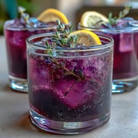 Vibrant purple lavender lemonade refresher with fresh lemon slices and lavender sprigs, offering a floral citrus twist on classic lemonade.