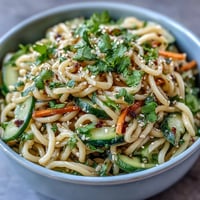 Cold Sesame Noodle Bowl with Cucumber, fresh and vibrant, featuring chilled noodles in creamy sesame sauce with crisp cucumber slices and herbs.  